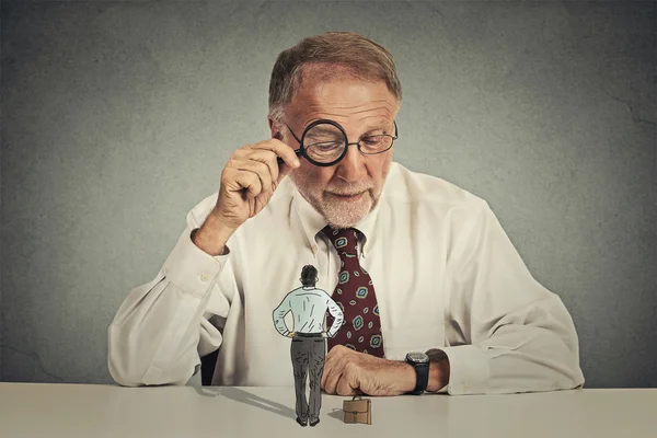 Corporate businessman looking through magnifying glass at employee — Stock Photo, Image