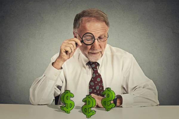 Business man looking through magnifying glass at dollar signs — Stock Photo, Image