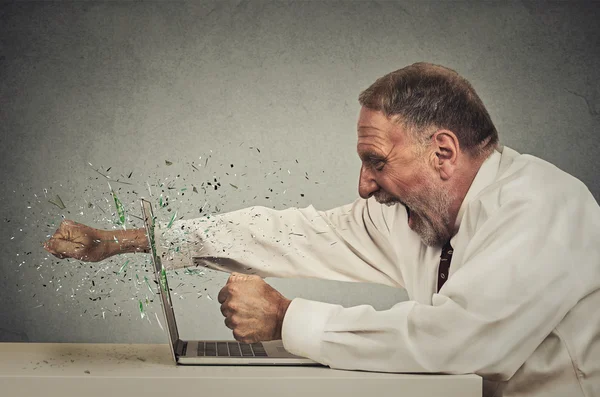 Furious senior businessman throws punch into computer — Stock Photo, Image