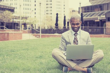 Handsome happy businessman working with laptop outdoors