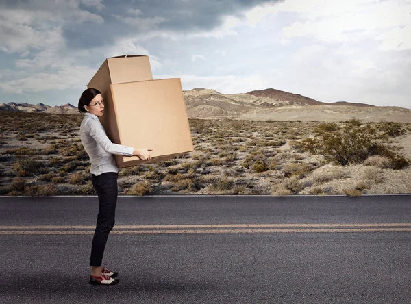 Young woman carrying heavy large box package — 图库照片