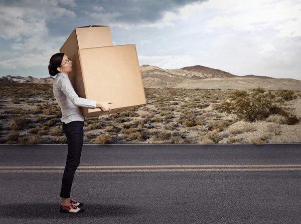 Молодая женщина с тяжёлой большой коробкой — стоковое фото