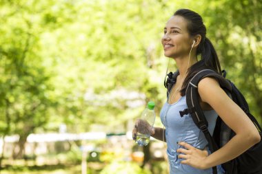 female hiker with backpack walking on country forest trail