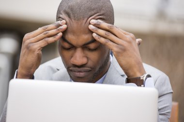 stressed man sitting outside corporate office working on computer