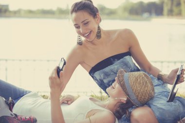 happy women friends laughing browsing social media on mobile devices 