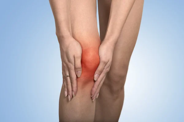 Tendon knee joint problems on woman leg indicated with red spot — ストック写真