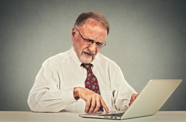 Confused senior man working on laptop computer 