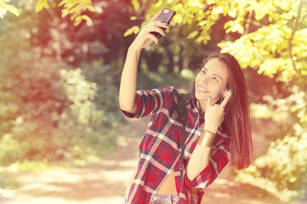 Молодая красивая женщина делает селфи со смартфоном в парке — стоковое фото