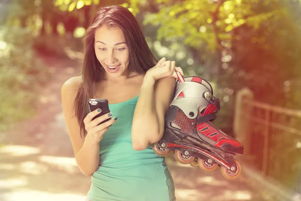 Mujer sorprendida con patines en línea leyendo noticias en el teléfono móvil — Foto de Stock