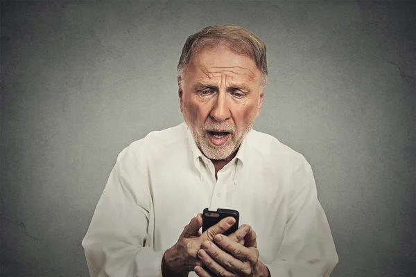 Пожилой человек, шокированный тем, что он видит в своем телефоне — стоковое фото