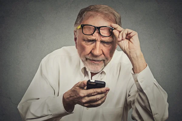 Uomo anziano con gli occhiali che hanno difficoltà a vedere il telefono cellulare — Foto Stock