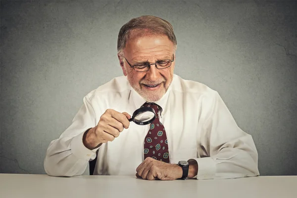 Senior businessman looking through a magnifying glass — ストック写真