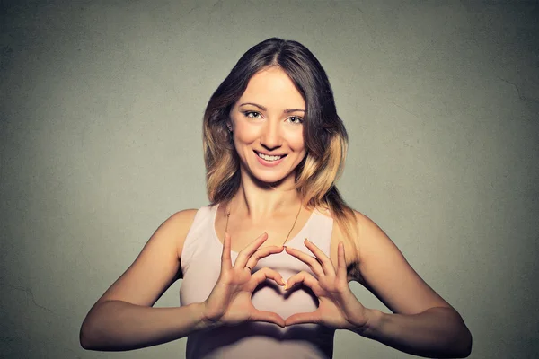 Sorridente allegra giovane donna felice che fa segno di cuore con le mani — Foto Stock