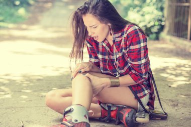 injured young woman suffering from pain sitting on the ground