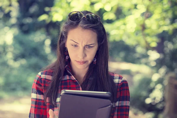 Skeptical unhappy serious woman using mobile pad computer outdoors — Stock Photo, Image