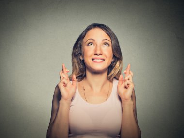 hopeful beautiful woman crossing her fingers looking up hoping
