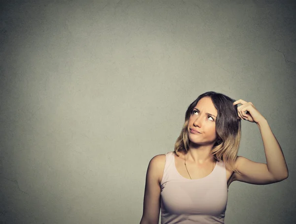 woman scratching head, thinking daydreaming about something looking up