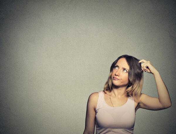 woman scratching head, thinking daydreaming about something looking up