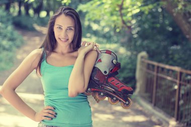 portrait happy young woman going rollerblading holding in line skates