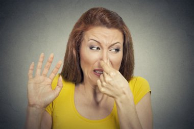 young woman disgusted by smell looks displeased, something stinks