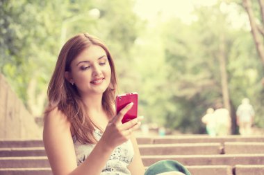 happy, cheerful, young woman excited by what she sees on cell phone texting 