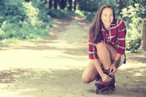 Girl going rollerblading sitting putting on in line skates outdoors — Stock Photo, Image