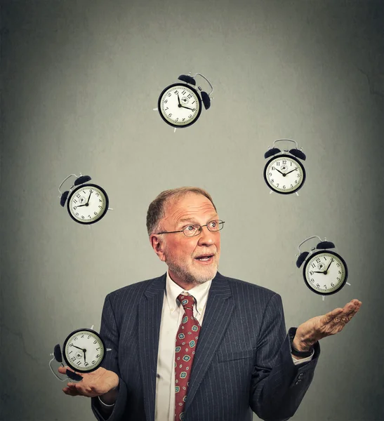 Business man in suit juggling multiple alarm clocks — Stockfoto