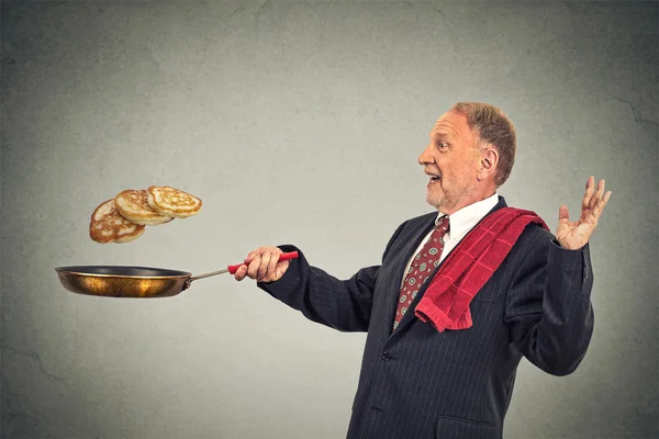 Happy smiling senior man tossing pancakes on frying pan — Zdjęcie stockowe