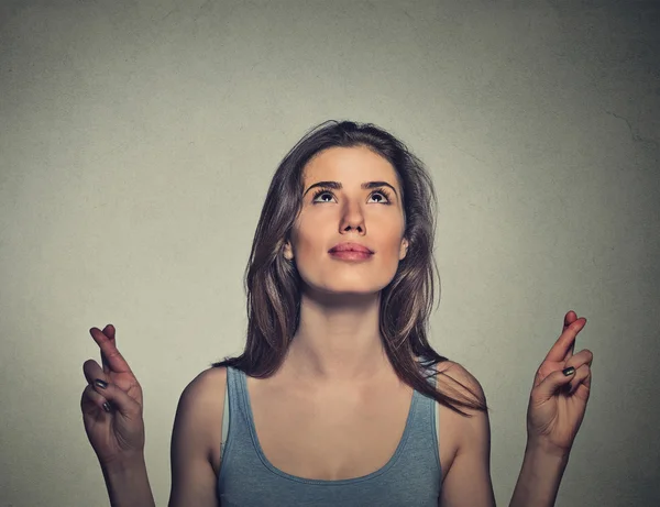 Young woman crossing her fingers looking up — ストック写真