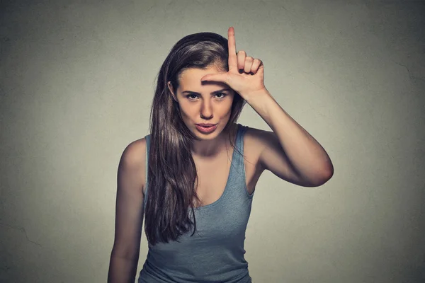 Young unhappy woman giving loser sign on forehead — Stock Photo, Image