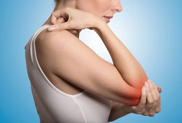 Woman with painful elbow on blue background — Stock fotografie