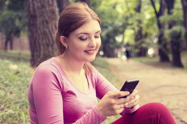 happy, cheerful, young woman excited by what she sees on cell phone texting 