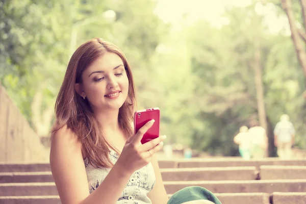 Gelukkig, vrolijke, jonge vrouw die opgewekt door wat ze op mobiele telefoon tekstberichten ziet — Stockfoto