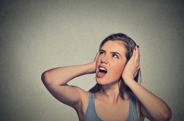 stressed woman covering her ears looking up