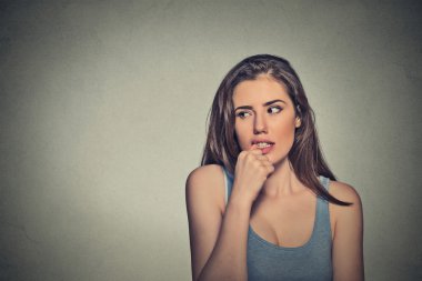nervous looking young woman biting her fingernails 