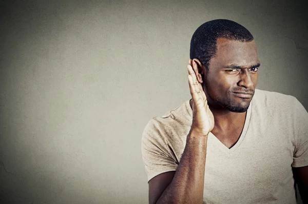 Young guy trying to secretly listen in on a conversation — Stockfoto