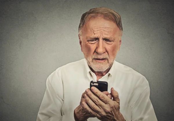 Besorgter älterer Mann blickt auf sein Smartphone — Stockfoto