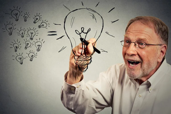 Senior excited businessman has an idea drawing a lightbulb with pen — Stockfoto