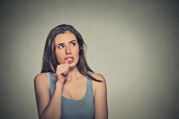 Nervous looking young woman biting her fingernails — Stockfoto