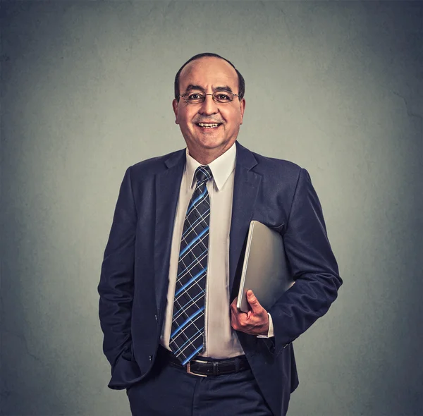 Hombre de negocios feliz con gafas y portátil de pie sobre fondo gris — Foto de Stock