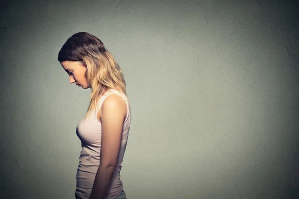 Triest eenzame vrouw neerkijkt geïsoleerd op grijze muur achtergrond — Stockfoto