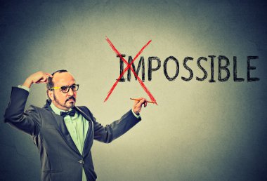 thoughtful man with glasses converting the word impossible to possible clipart