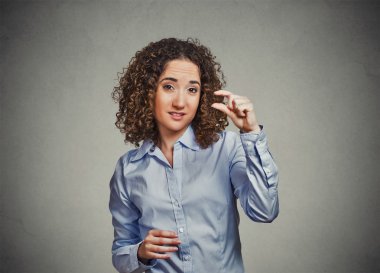 skeptical young woman showing small amount gesture with hand fingers clipart