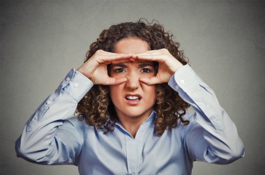 Displeased young woman looking through fingers like binoculars