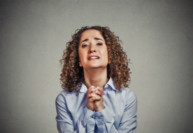 young woman gesturing with clasped hands, pretty please with sugar on top