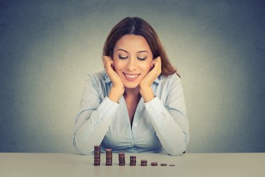 uccessful business woman sitting at table looking at growing stack of coins
