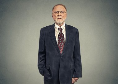 Portrait of a serious senior businessman on gray wall background
