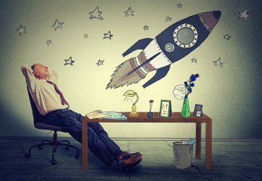 business man relaxing at his desk in office daydreaming of space tourism
