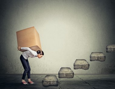 Difficult task concept. Young woman carrying heavy box upstairs clipart
