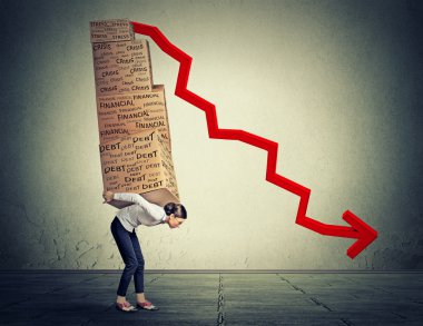 Young woman carrying heavy boxes full of financial debt walking along gray wall background